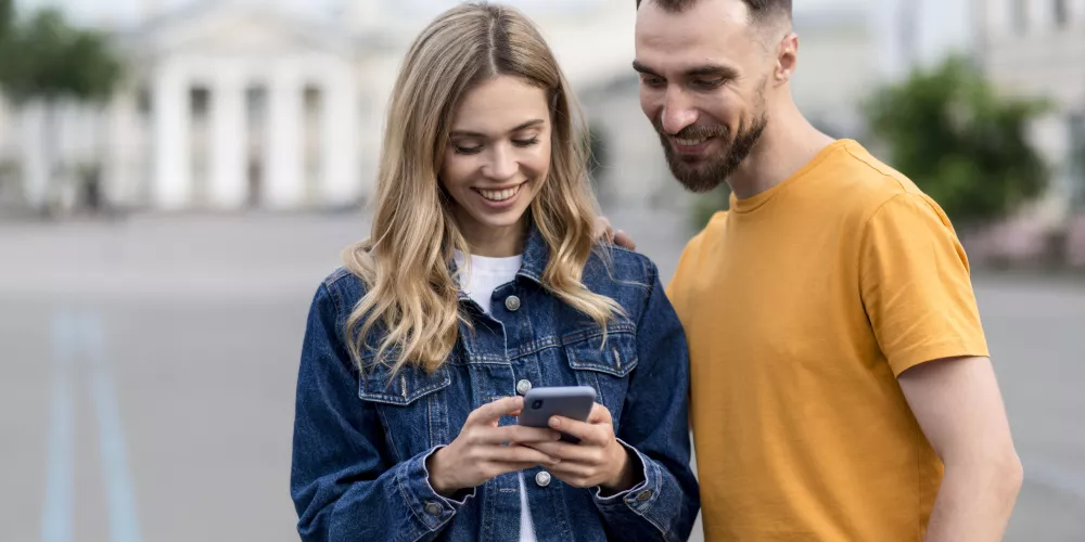 Une femme et un homme regardant l'écran d'un smartphone