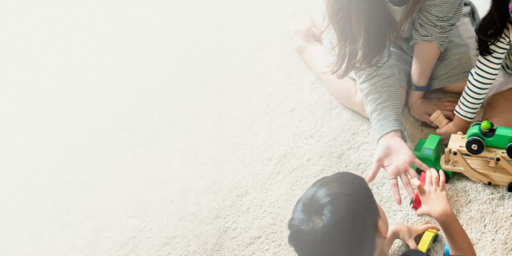 japanese-family-playing-with-toys-on-the-floor-design-space-banner.jpg