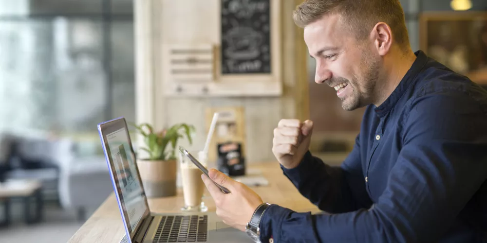 happy-freelancer-with-tablet-and-laptop-computer-in-coffee-shop-scaled.jpg