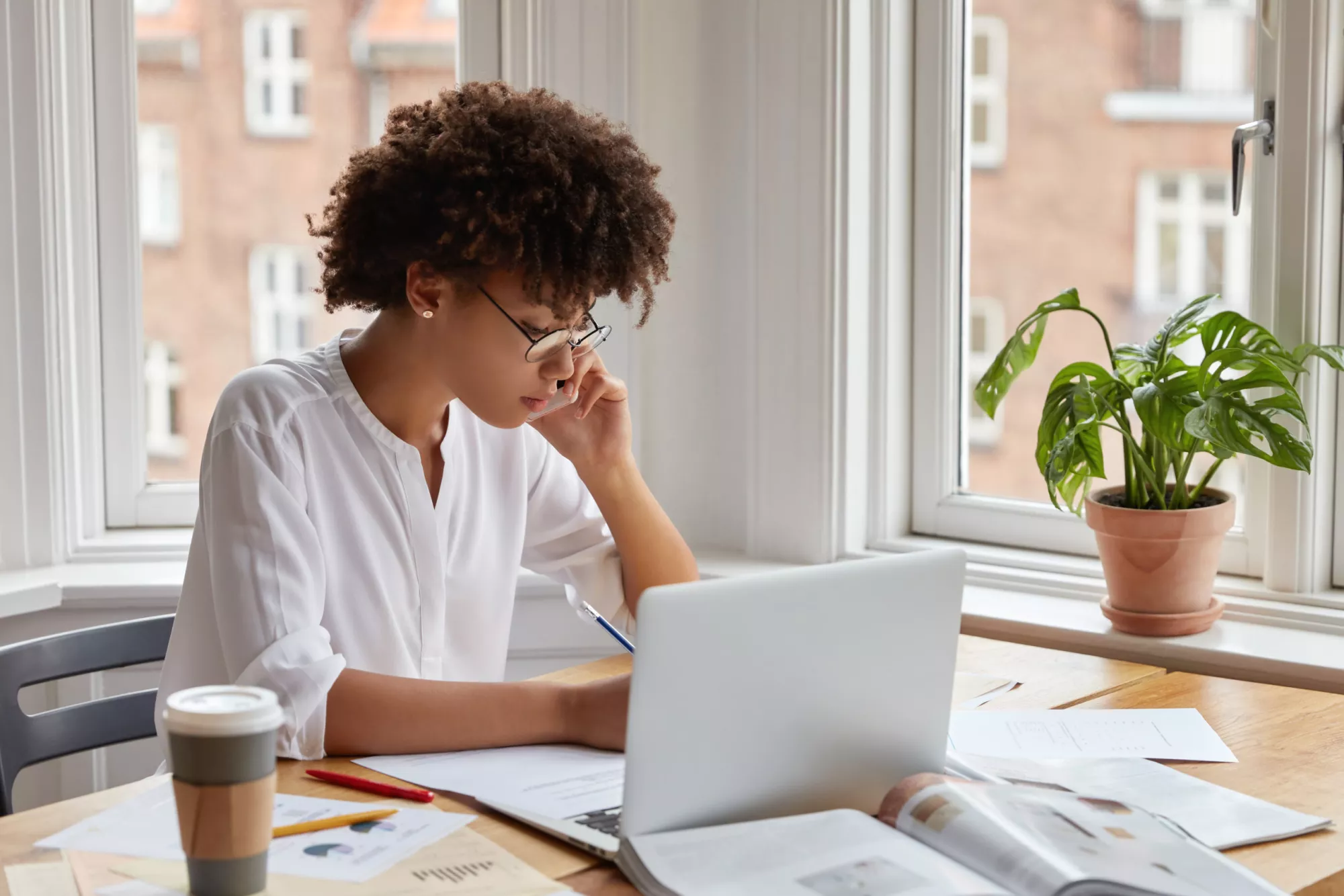 dark-skinned-female-specialist-studies-graphs-statistics-has-phone-conversation-with-business-partner-scaled.jpg