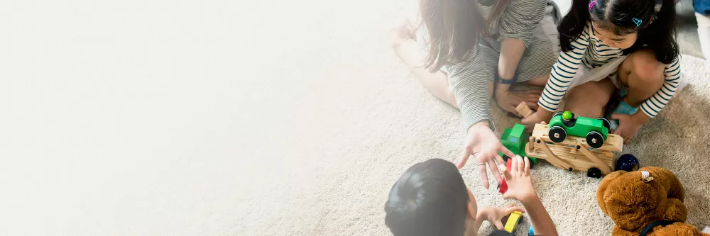 japanese-family-playing-with-toys-on-the-floor-design-space-banner.jpg