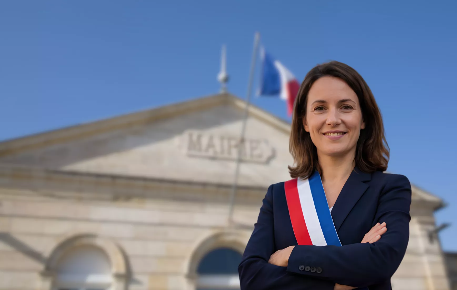 Élue municipale devant une mairie illustrant la communication municipale avec les citoyens d’une commune